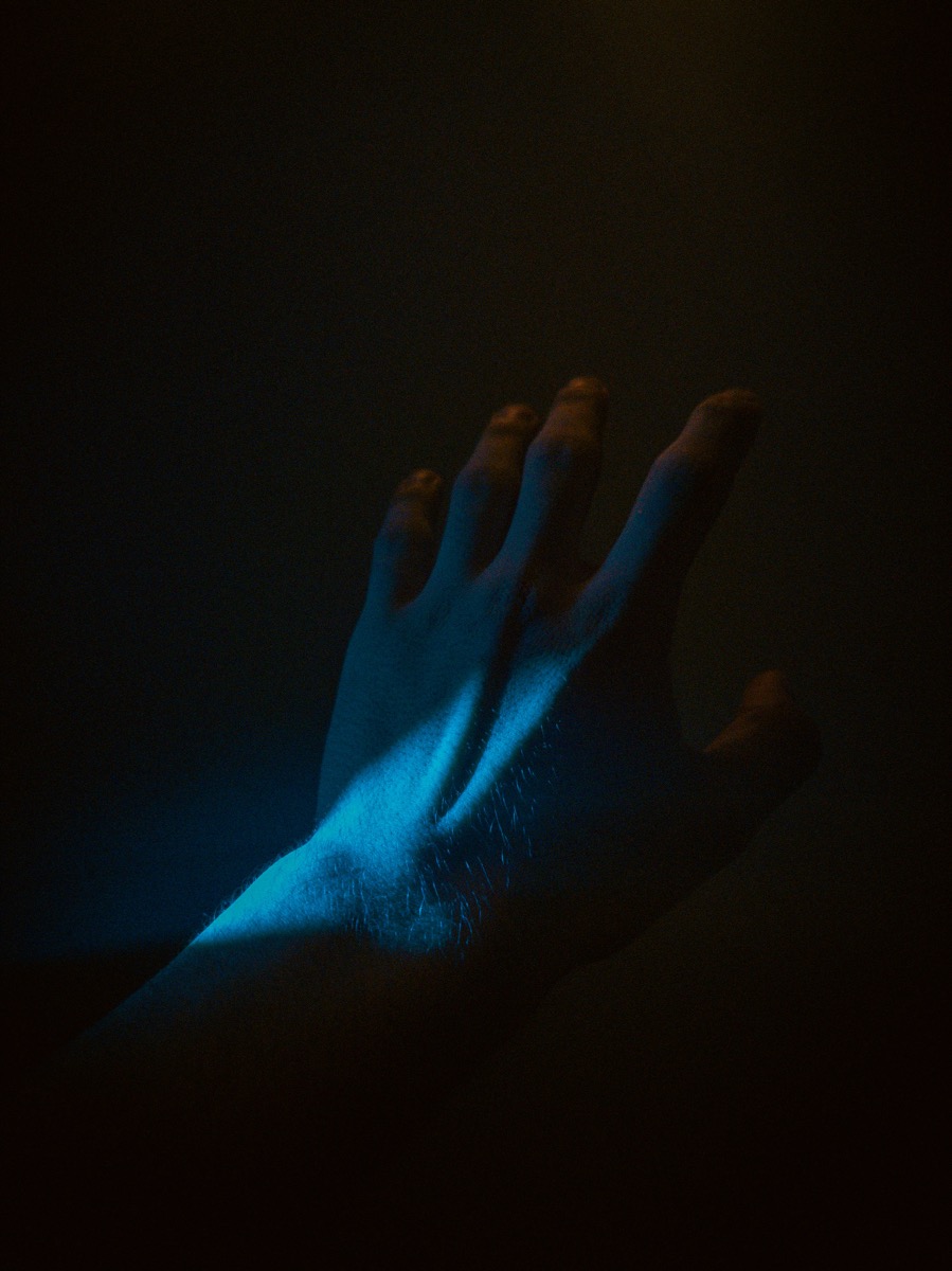 Main éclairée par une lumière bleue dans l'obscurité — magie digitale